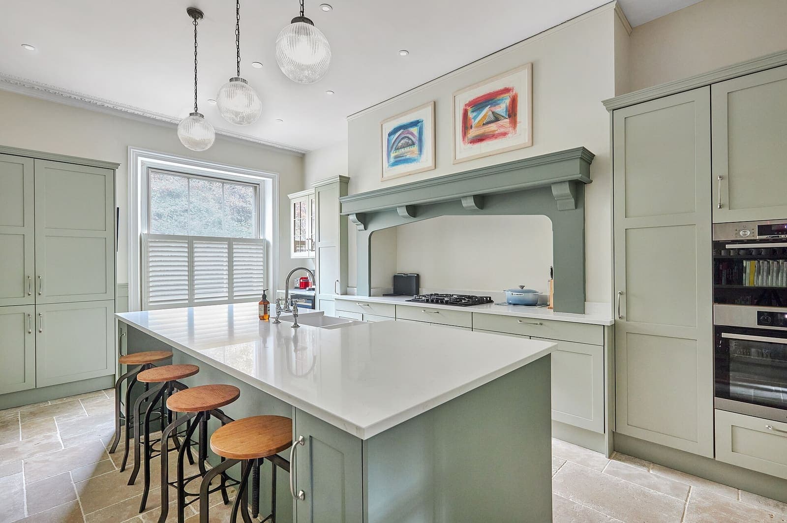 A newly renovated luxury kitchen with sage-green cabinetry and a quartz countertop
